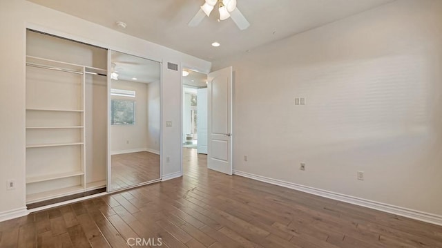 unfurnished bedroom with ceiling fan, dark wood-type flooring, and a closet