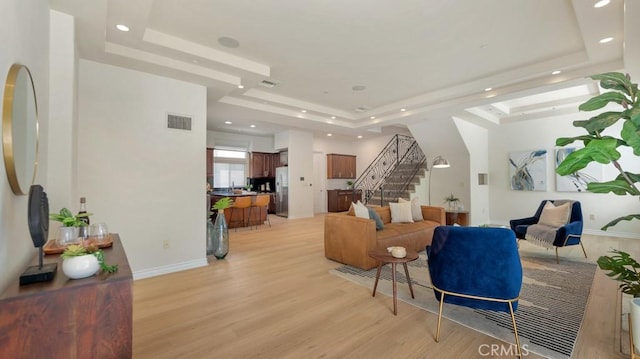 living room featuring light wood-type flooring and a tray ceiling