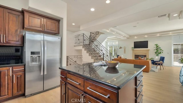 kitchen featuring stainless steel fridge, light hardwood / wood-style flooring, a center island, and plenty of natural light