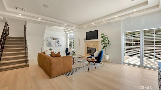 living room with a raised ceiling and light hardwood / wood-style flooring