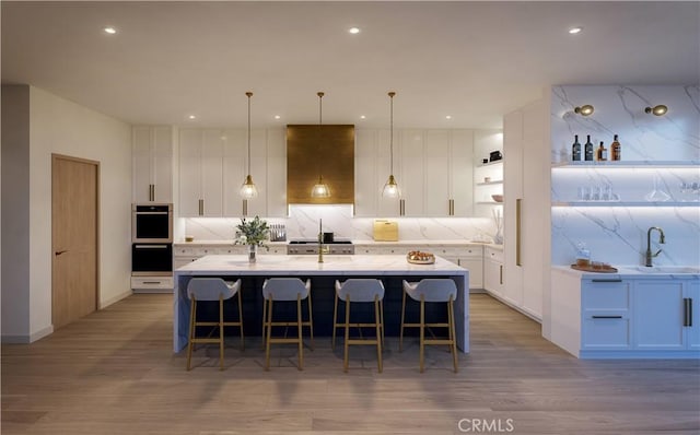 kitchen featuring white cabinetry, a kitchen island with sink, and light hardwood / wood-style floors