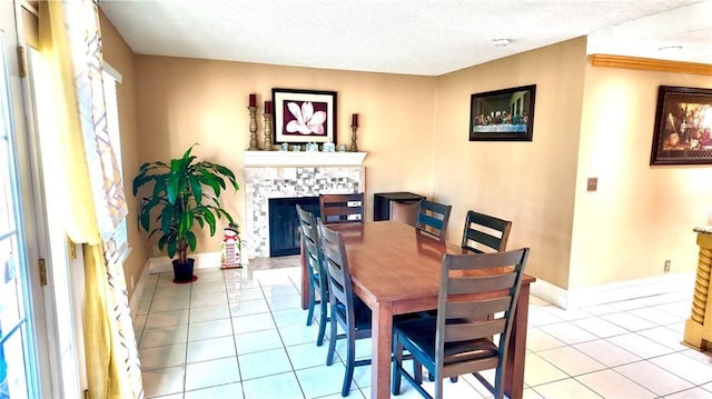 dining area with a tile fireplace, a textured ceiling, and light tile patterned flooring