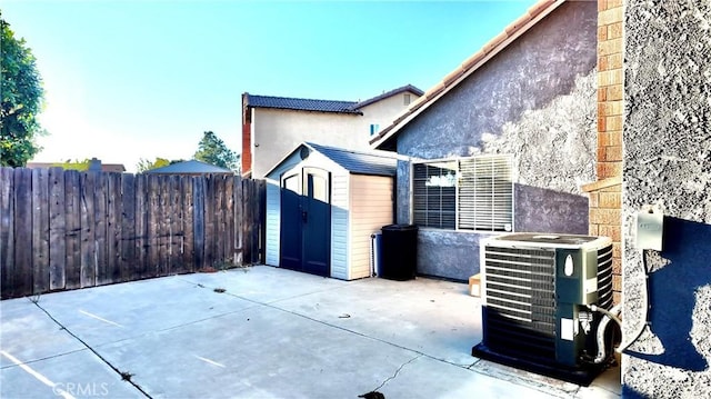 view of patio with central air condition unit and a shed