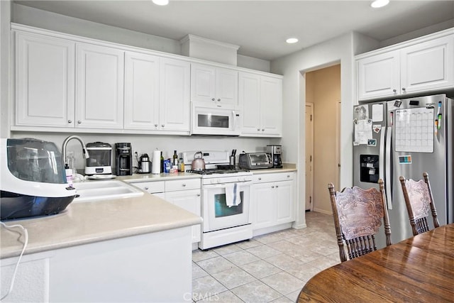 kitchen with white cabinets, light tile patterned floors, white appliances, and sink