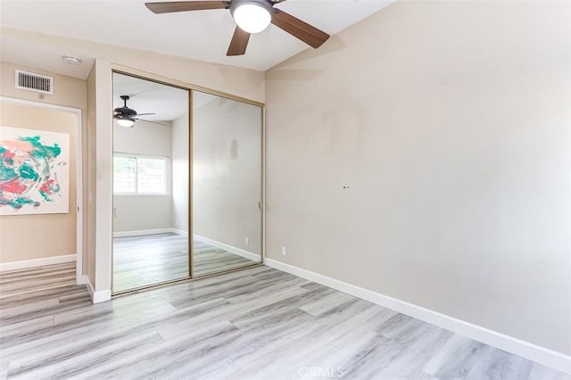 unfurnished bedroom with light hardwood / wood-style floors, vaulted ceiling, a closet, and ceiling fan