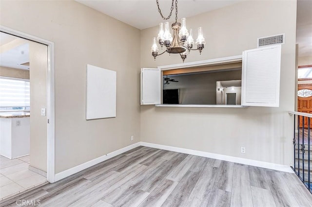 unfurnished dining area featuring ceiling fan with notable chandelier and light hardwood / wood-style flooring