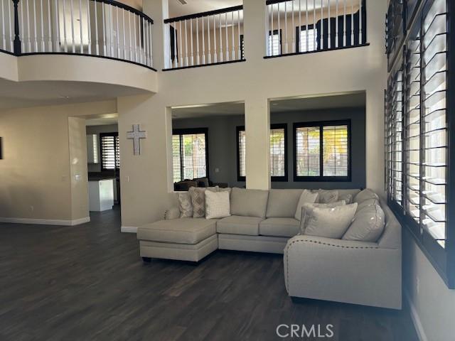 living room with plenty of natural light, dark wood-type flooring, and a high ceiling