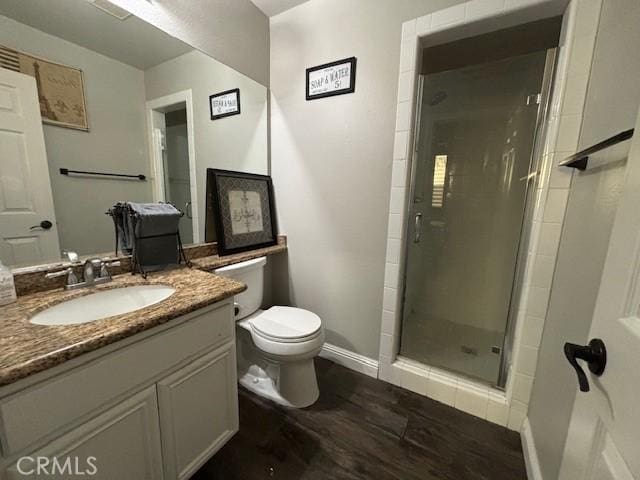 bathroom with hardwood / wood-style floors, vanity, toilet, and a shower with door