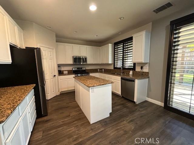 kitchen featuring appliances with stainless steel finishes, a center island, white cabinetry, and a healthy amount of sunlight