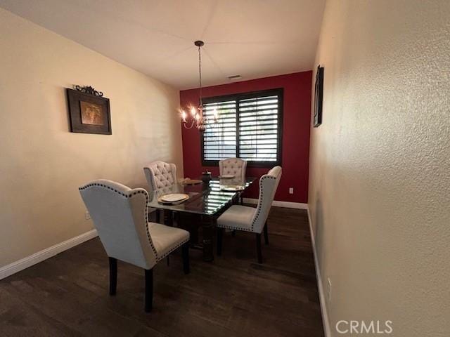 dining area with dark hardwood / wood-style floors and a notable chandelier