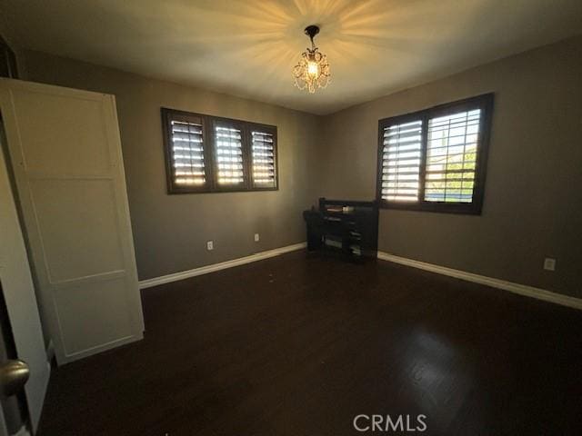 unfurnished bedroom with dark wood-type flooring and a notable chandelier