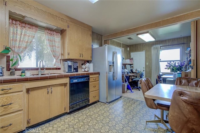 kitchen with tile counters, stainless steel fridge, dishwasher, and plenty of natural light