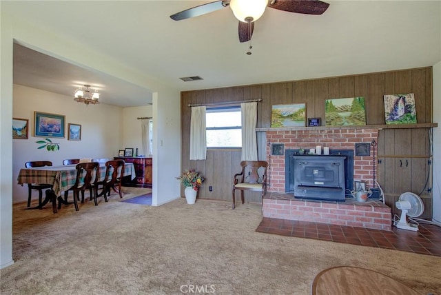 living room featuring carpet, ceiling fan with notable chandelier, and wooden walls