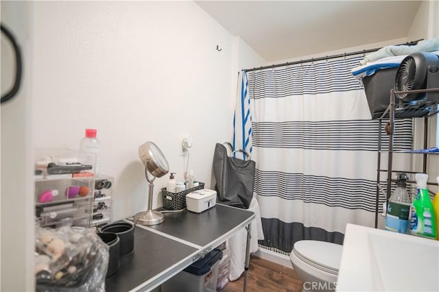 bathroom with toilet, hardwood / wood-style flooring, and curtained shower