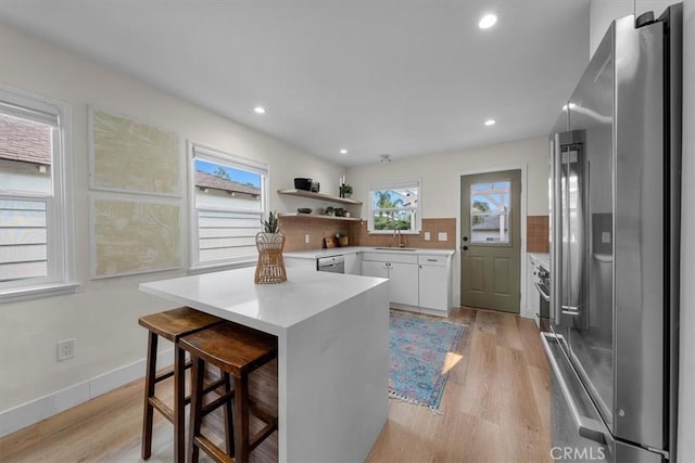 kitchen featuring white cabinets, a kitchen bar, stainless steel appliances, decorative backsplash, and sink