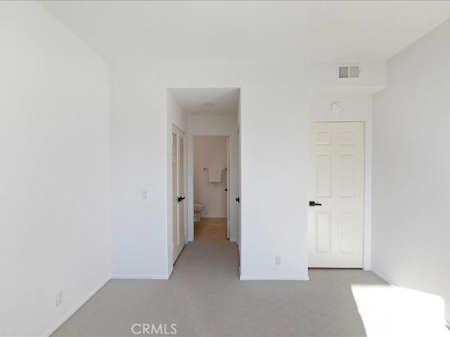 unfurnished bedroom with baseboards, light carpet, and visible vents