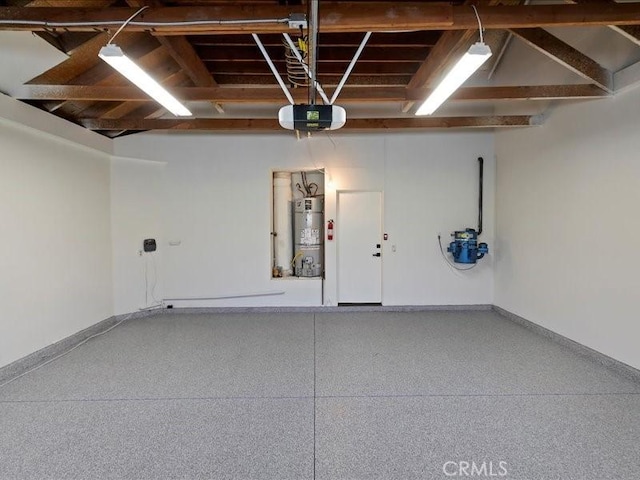 garage with baseboards, a garage door opener, and strapped water heater