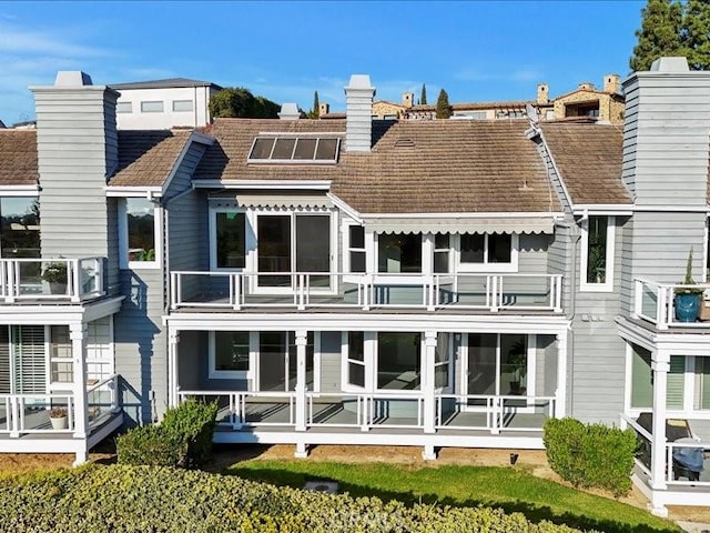 rear view of property featuring french doors, a balcony, and a chimney