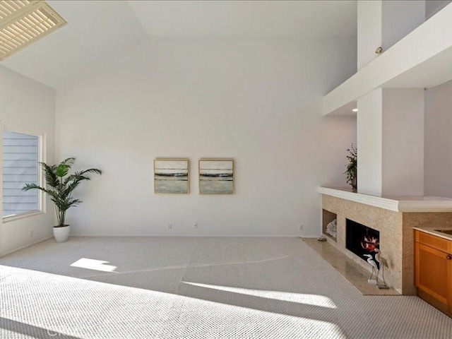 living room with a high end fireplace, light colored carpet, and vaulted ceiling