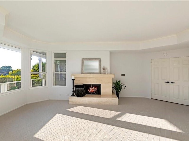 unfurnished living room featuring baseboards, a lit fireplace, and carpet