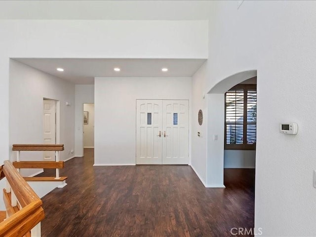entrance foyer featuring arched walkways, baseboards, recessed lighting, and wood finished floors