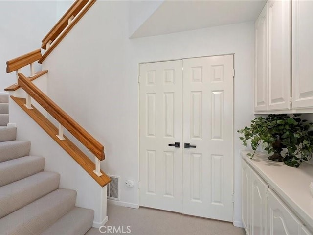 staircase with carpet floors, baseboards, and visible vents