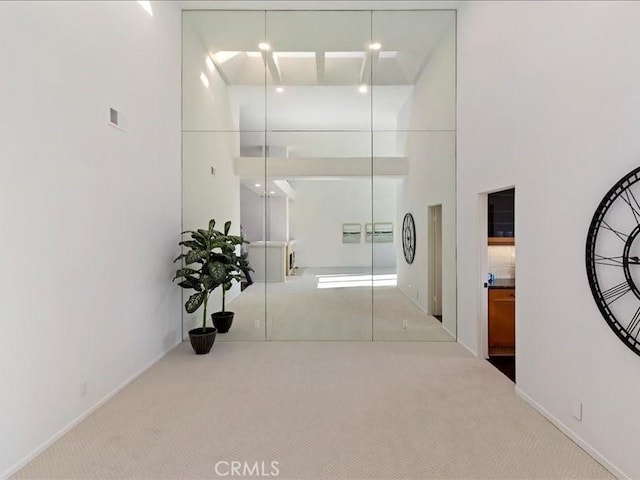 hall with light carpet and a towering ceiling