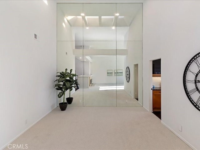 hall with baseboards, carpet, and a high ceiling