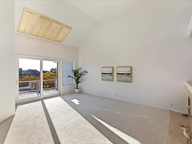 empty room with high vaulted ceiling and light carpet