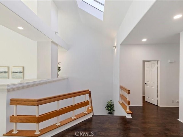 hallway featuring a skylight, dark hardwood / wood-style flooring, and a towering ceiling