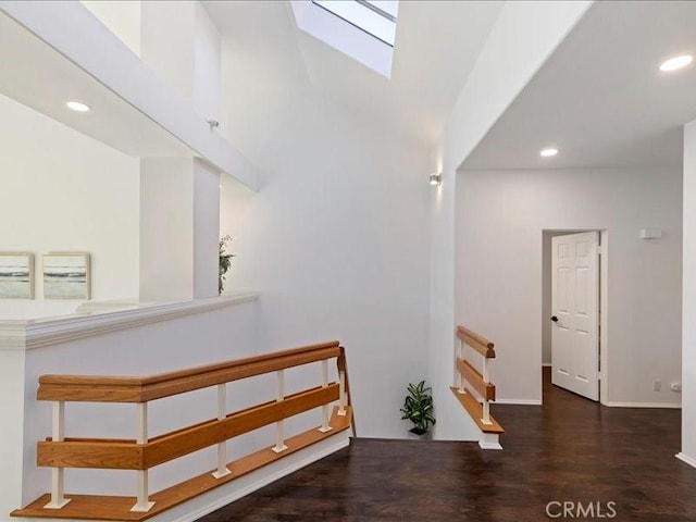hall featuring recessed lighting, baseboards, wood finished floors, and lofted ceiling with skylight