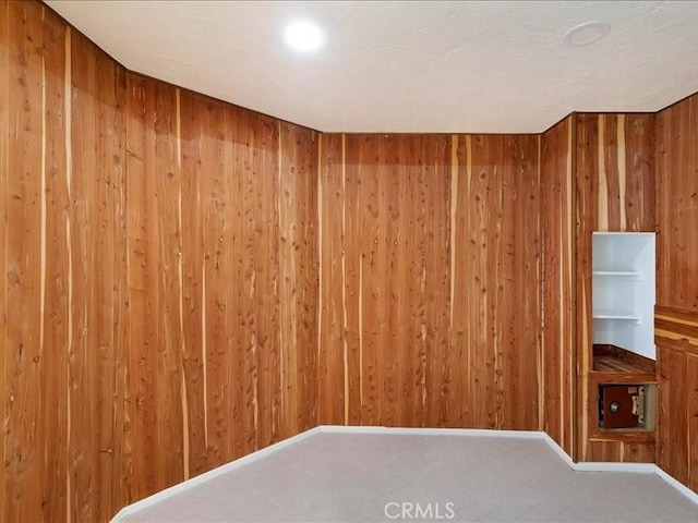 carpeted empty room with wood walls