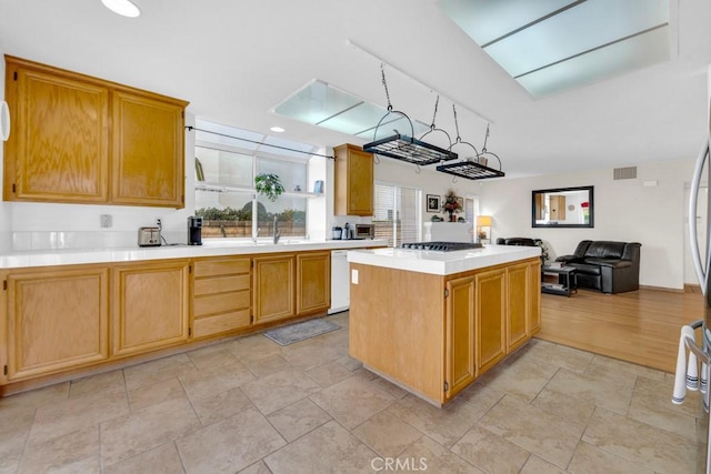 kitchen featuring stainless steel gas stovetop, sink, white dishwasher, and a center island