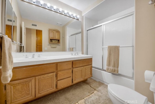 full bathroom featuring toilet, vanity, and shower / bath combination with glass door