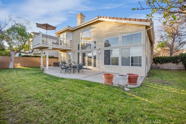 back of house with a balcony, a lawn, and a patio