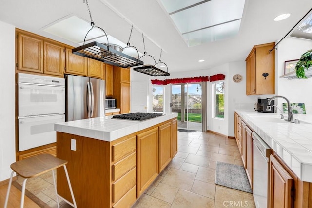 kitchen featuring tile counters, stainless steel appliances, light tile patterned flooring, a kitchen island, and sink