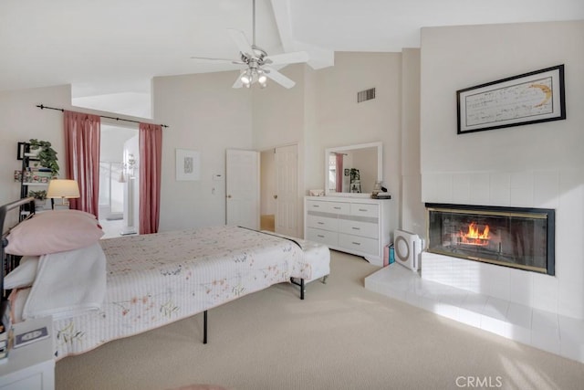 carpeted bedroom with ceiling fan, a tile fireplace, and high vaulted ceiling