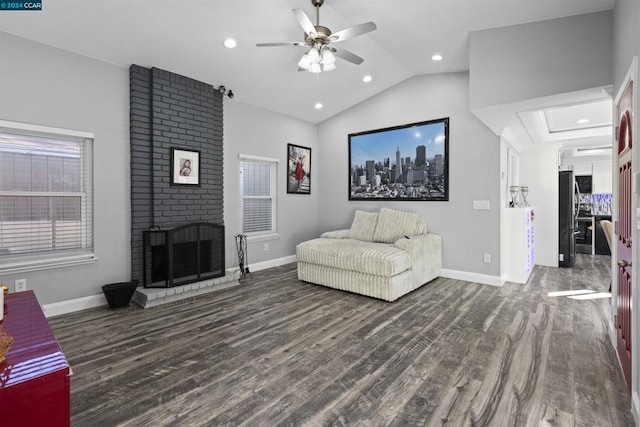 living room featuring ceiling fan, lofted ceiling, dark wood-type flooring, and a brick fireplace