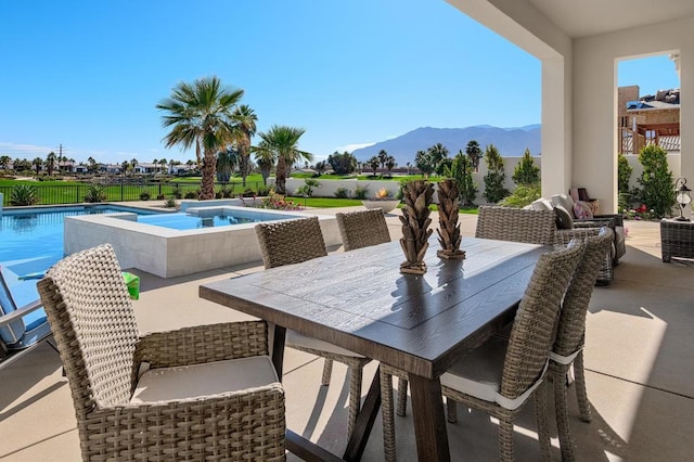 view of patio with a swimming pool with hot tub and a mountain view