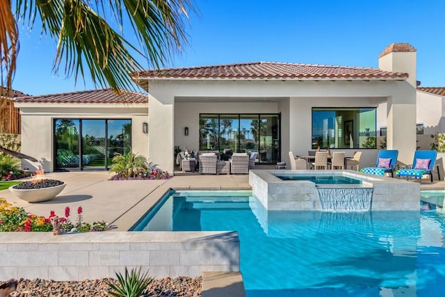 rear view of house with a pool with hot tub, an outdoor living space with a fire pit, and a patio