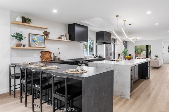 kitchen with pendant lighting, plenty of natural light, light wood-type flooring, and stainless steel appliances