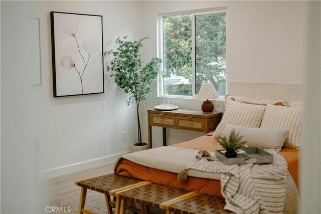 bedroom with baseboards, wood finished floors, and multiple windows