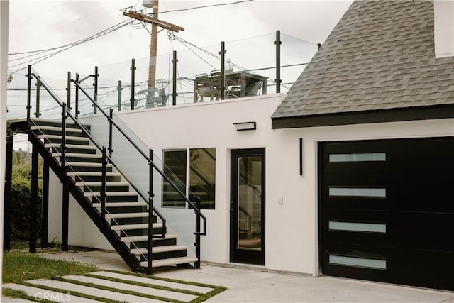 property entrance with a shingled roof and stucco siding