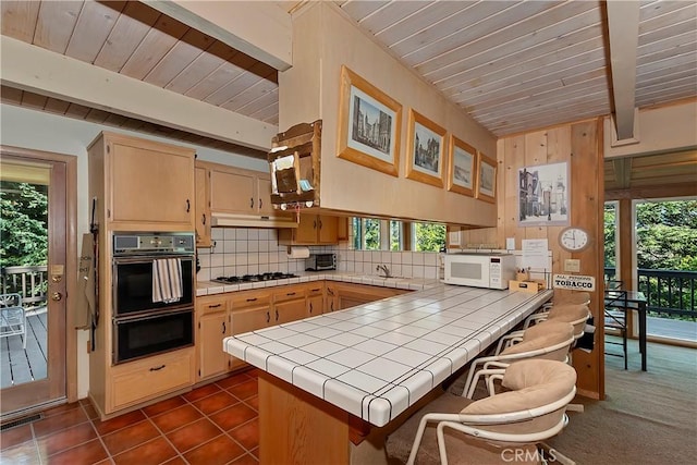 kitchen with kitchen peninsula, tile countertops, and plenty of natural light