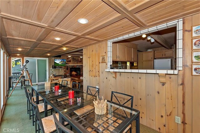 carpeted dining space featuring wood ceiling and wooden walls