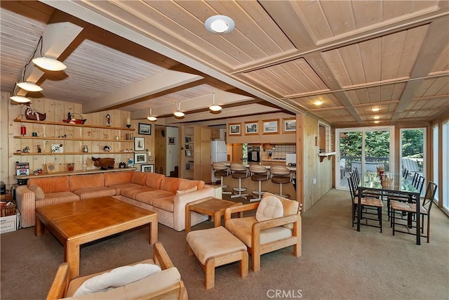 carpeted living room with beam ceiling and wooden walls