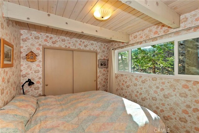 bedroom featuring beam ceiling, a closet, and wooden ceiling