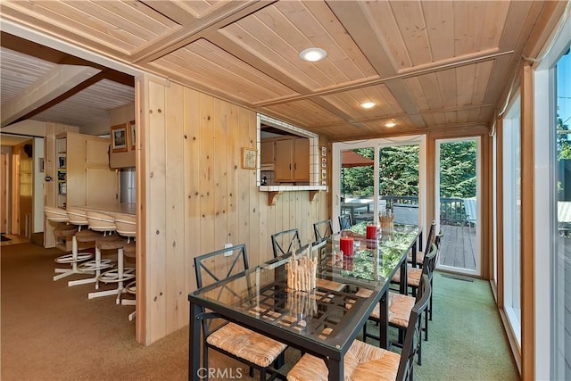 dining area with light carpet, wooden ceiling, and wood walls