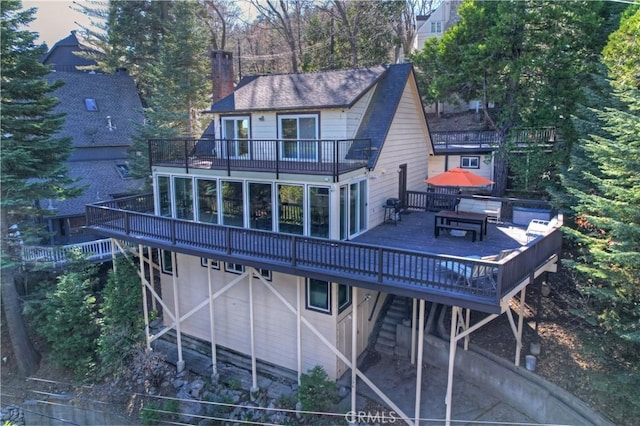 back house at dusk with a balcony and a wooden deck