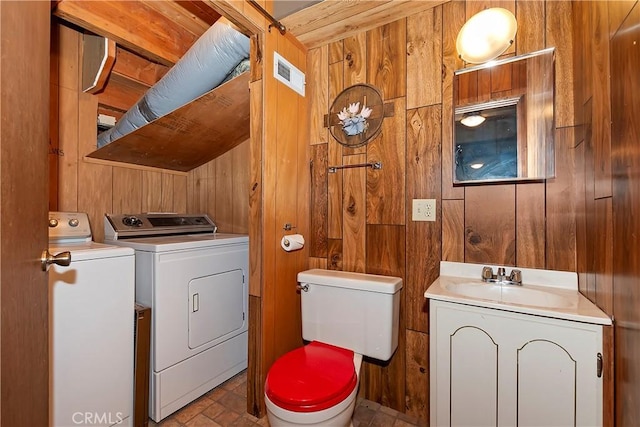 bathroom featuring wooden walls, toilet, vanity, and independent washer and dryer